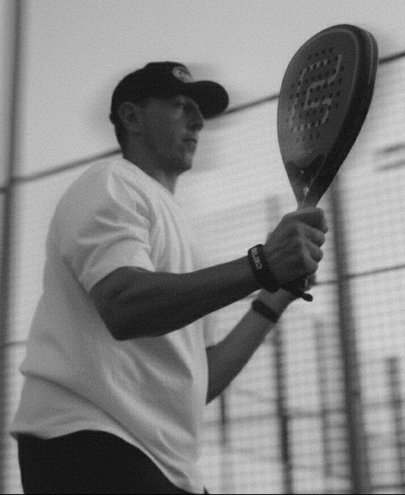 Person holding a tennis racket on a court with a blurred background